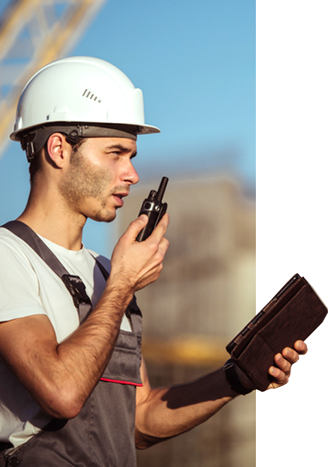  A construction worker speaks into a walkie-talkie while using an iPad as workforce mobility tool